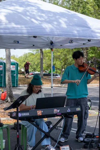 A photo of a musical performance at Goblin Market featuring a keyboardist and violinist playing underneath a tent.
